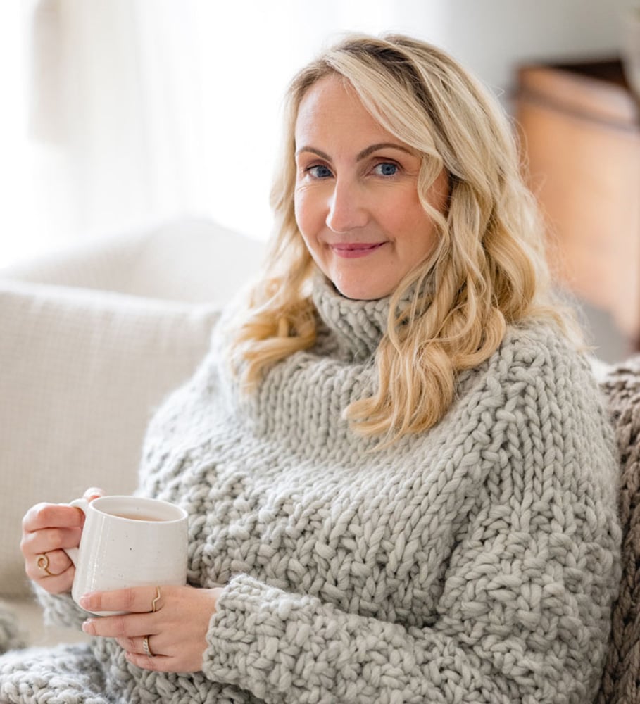 Louise smiling wearing an oversized knitted sweater