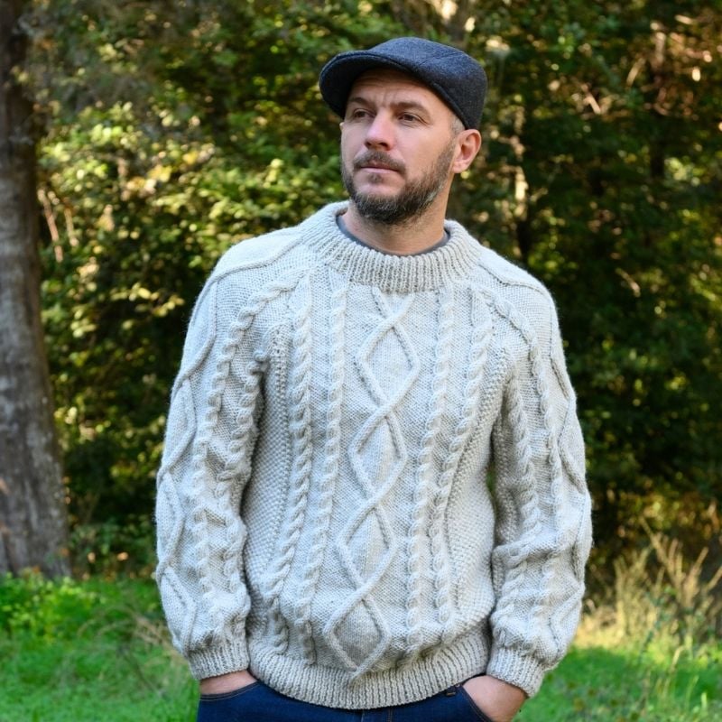 This Aran sweater knitting pattern will work up into the perfect cable knit you need to stay cozy!