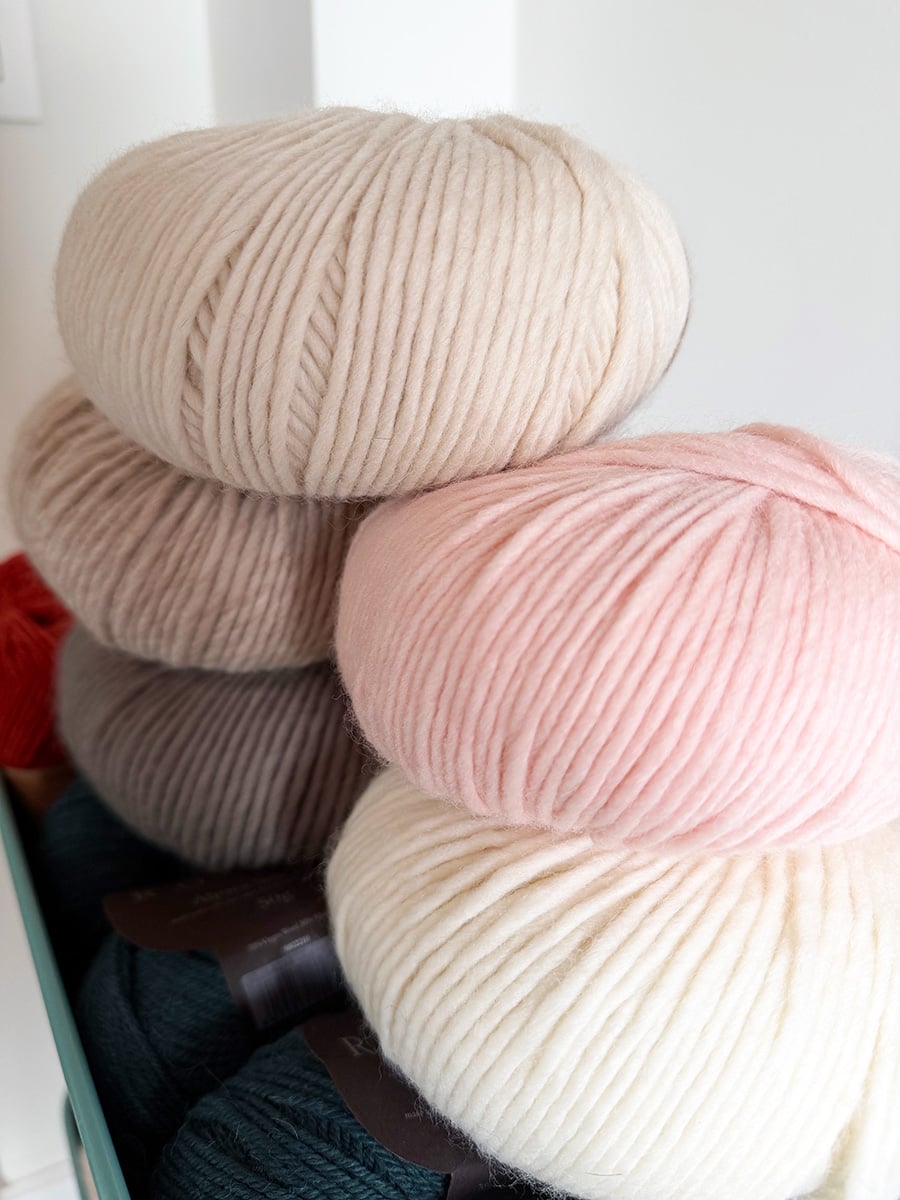 Petite Wool bulky yarn balls stacked in cream, beige, gray and pale pink.