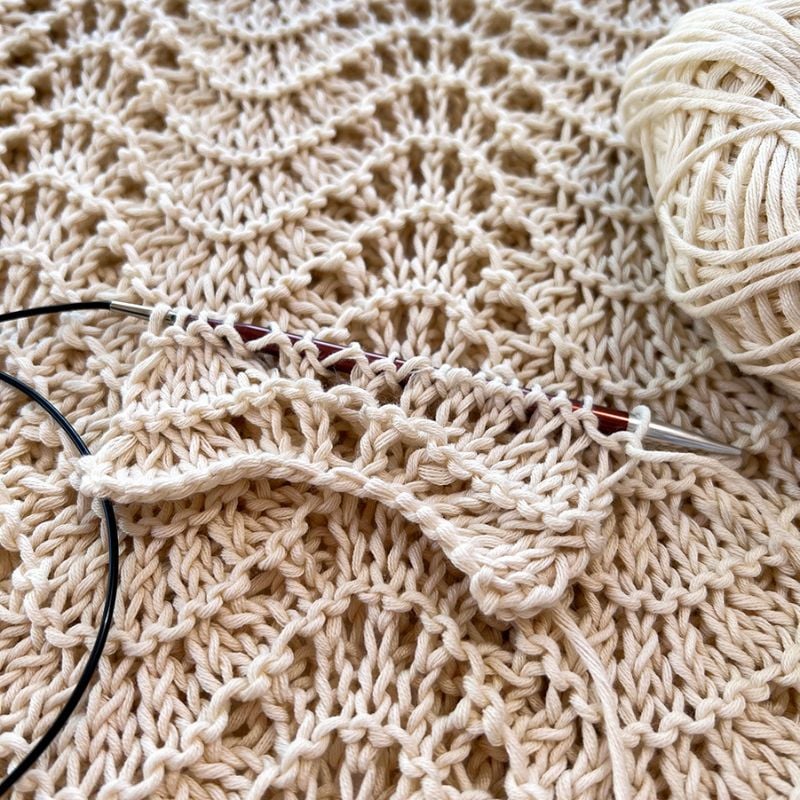 The ripple stitch knitting pattern on the needles in white cotton