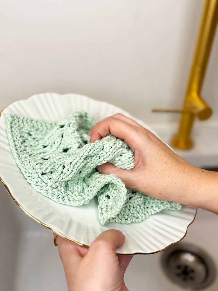 cleaning a plate with a knitted cotton dishcloth